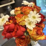 A bouquet of vibrant pink and yellow roses with a few green leaves poking through